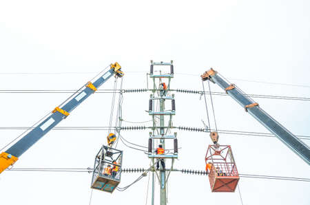 Electricians are climbing on electric poles to install and repair power lines.の写真素材