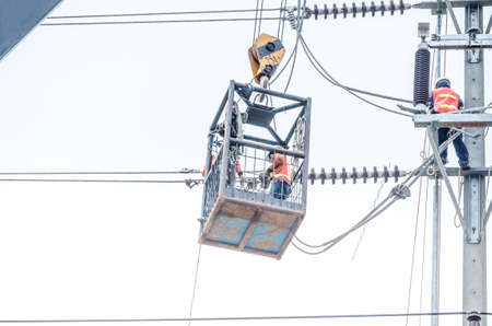 Electricians are climbing on electric poles to install and repair power lines.の写真素材