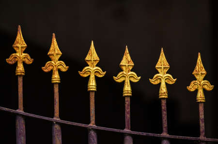 Closeup of the top of old steel fence with dark background.の写真素材
