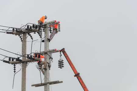 Electricians are climbing on electric poles to install and repair power lines.の写真素材