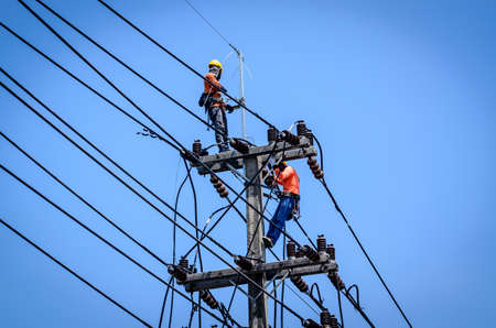 Electricians are climbing on electric poles to install and repair power lines.の写真素材