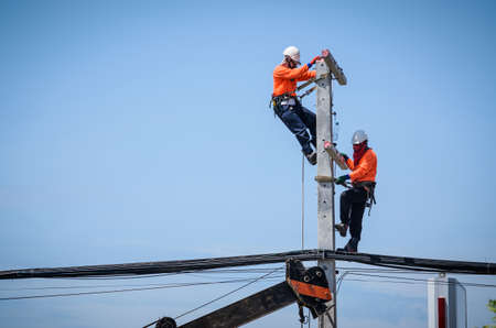 Electricians are climbing on electric poles to install and repair power lines.の写真素材