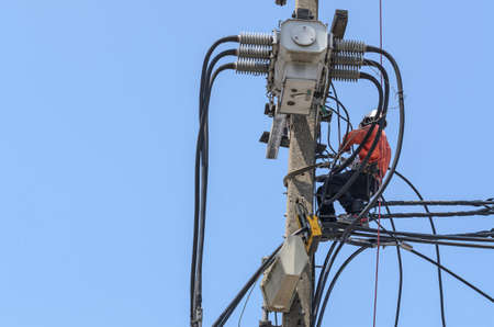 Electricians are climbing on electric poles to install and repair power lines.の写真素材