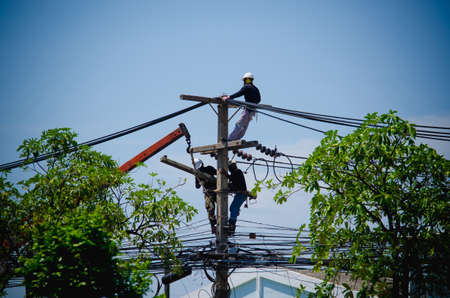 Electricians are climbing on electric poles to install and repair power lines.