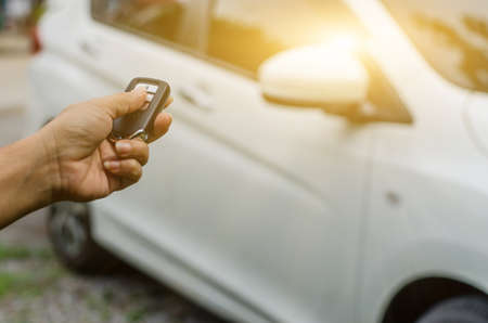 Car remote control by smart key, Hand holding smart key to lock doors of white carの写真素材