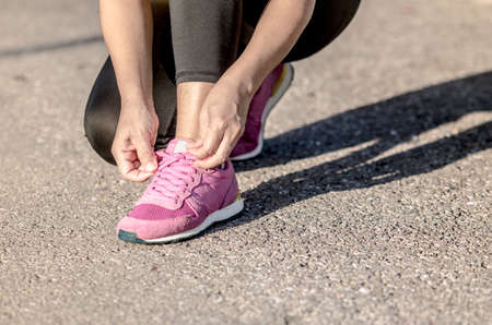 young womam is sitting tying running shoes before to run in the park.の写真素材