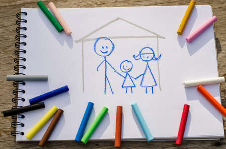 Crayon drawing of a happy family, School notebooks and stationery on wooden planks. Back to school...