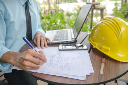 Close-up shot of a civil engineer writing a note in a notebook for architecture.の写真素材
