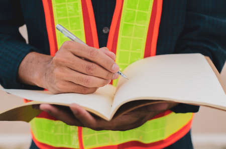 Hand of male engineer and notebook, male engineer use writing pen to recordの写真素材