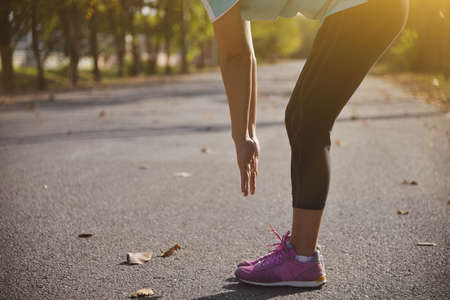 Closeup at hand and foot of women stretching after sport in the park background and sunrise in...