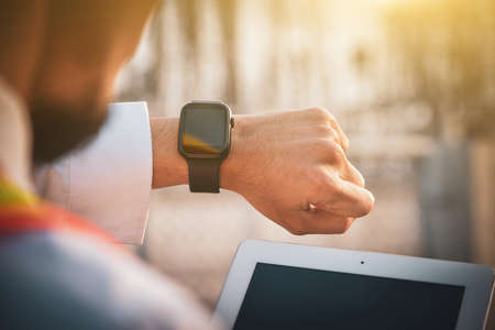 An electrician looks at the time on a black smart watch while working at workplace.の写真素材