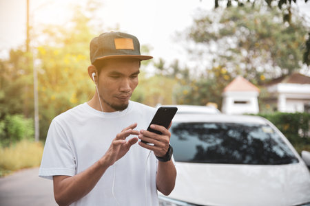 Young Asian man listens to music on his mobile phone.