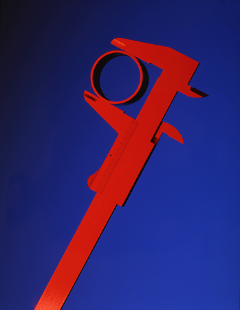 Red Callipers measuring section of pipe on blueの写真素材