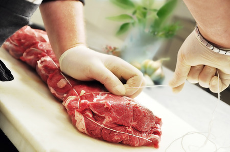 Detail of Hands that Tie Roast Meat on cutting boardの写真素材