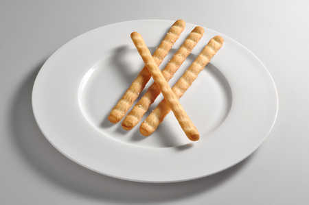Round dish with salted breadsticks isolated on grey backgroundの写真素材