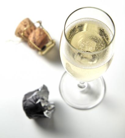Top view of sparkling glass flute and caps on white tableの写真素材