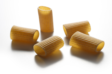 Selective focus on Some pieces of macaroni wholemeal pasta isolated on white backgroundの写真素材