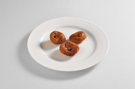 Round dish with portion of dried figs isolated on grey backgroundの写真素材