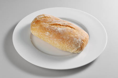 Round dish with bread roll Ciabatta isolated on grey backgroundの写真素材