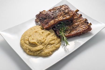 White rectangular plate with baked pork ribs and cornmeal mush isolated on white backgroundの写真素材