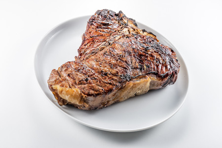 White round plate with Whole grilled T-bone steak isolated on white backgroundの写真素材
