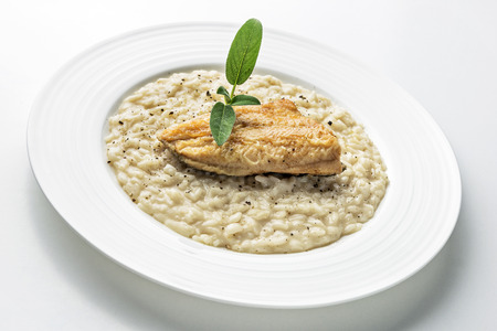 Parmesan risotto dish with trout fillet isolated on white backgroundの写真素材