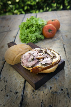 Sandwich with porchetta Roasted rolled pork on cutting board with salad and tomatoesの写真素材