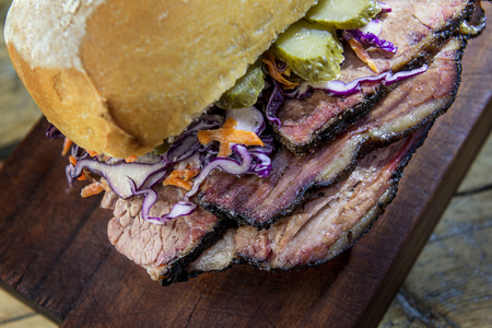 Detail of Brisket Sandwich with cucumber and coleslow on wooden cutting boardの写真素材
