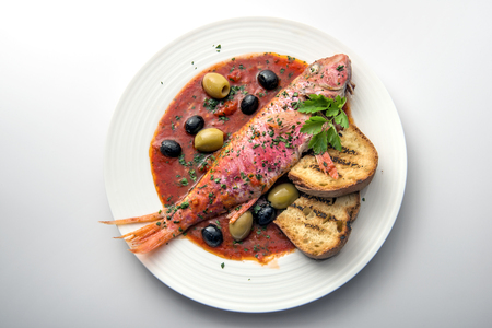 Dish of mullet fish with tomato and parsley isolated on whiteの写真素材