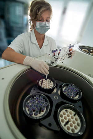 Milan, Italy - March 17, 2020: The operator inserts blood tubes into the centrifuge for medical analysisのeditorial素材