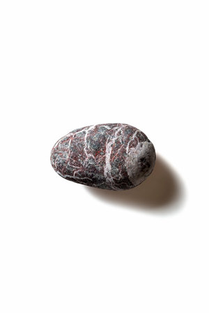 Single pebble with shadow on white background