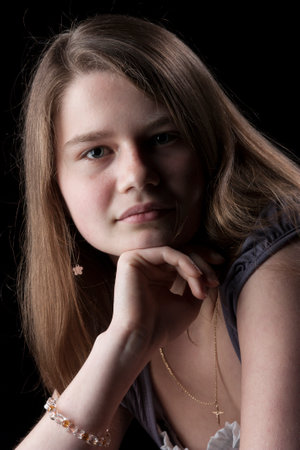 Portrait of young girl with long brown hair on black backgroundの写真素材