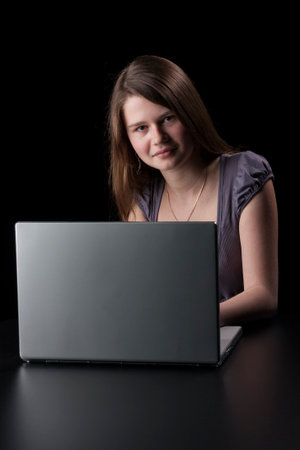 Young girl with long brown hair to the laptop on black backgroundの写真素材