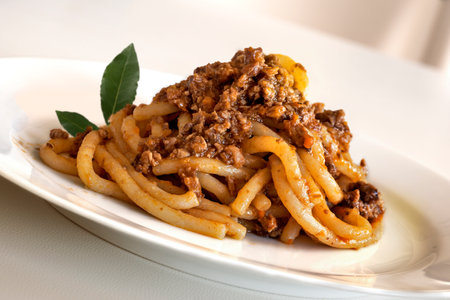 Dish of pici with wild boar ragout with bay leaves in white plateの写真素材