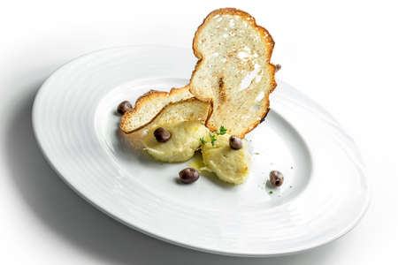 Plate of Ligurian-style cod fish with crispy bread and olives on white backgroundの写真素材