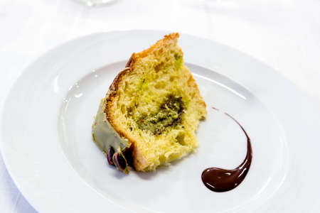 Plate with a slice of Sicilian pistachio panettone isolated on white background