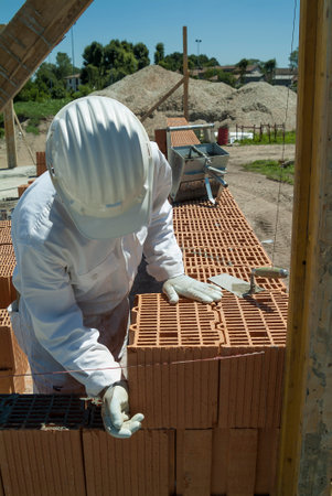 Red brick wall construction with bricklayer in construction siteの写真素材