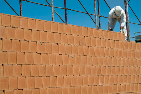 Red brick wall construction with bricklayer in construction siteの写真素材
