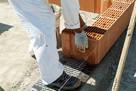 Red brick wall construction with bricklayer in construction siteの写真素材