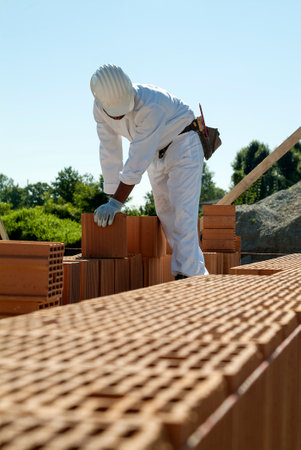 Red brick wall construction with bricklayer in construction siteの写真素材