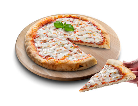 Classic round margherita pizza sliced on wooden cutting board and hand with sliceの写真素材