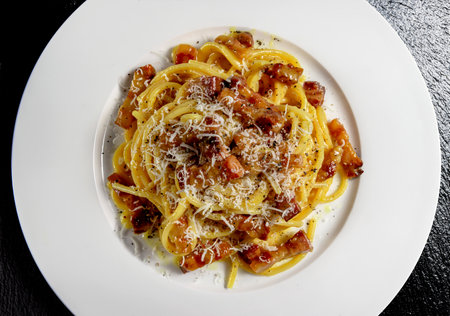 Detail Top view of plate with spaghetti carbonara and grated cheese on black stone backgroundの写真素材