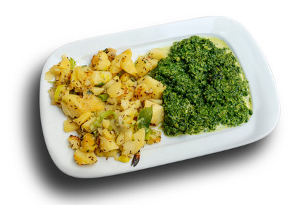 Rectangular dish with chopped spinach and potatoes and spring onion on white backgroundの写真素材