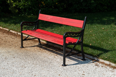 Empty Bench in wrought iron and red painted wood in park path