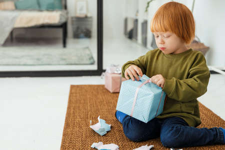 Little red haired boy unpacking Christmas presentの写真素材