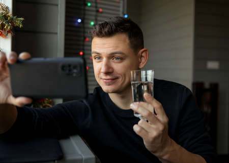 Young man with glass making video calling to congratulate Merry Christmas his relatives.の写真素材