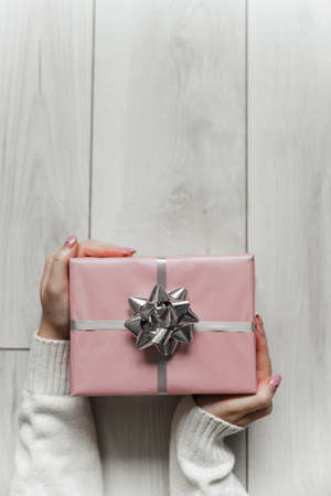 Hands hold pink christmas present on gray isolated backgroundの写真素材