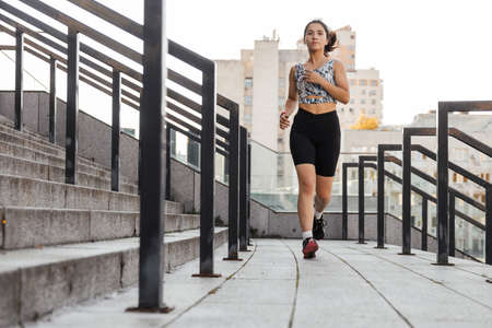 Teenage girl doing jogging near stadium outdoors of the city backgroundの写真素材