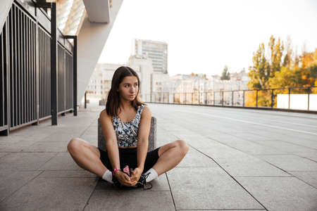 Teenage girl sitting on the floor and resting after training of the city the backgroundの写真素材