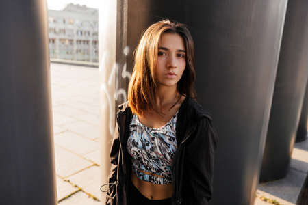 Close up portrait of a young teenage girl in sportswear on a dark urban background